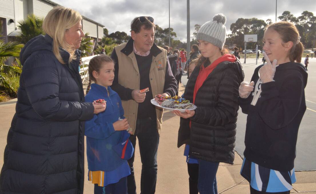 FUNDRAISING: Minister for Regional Youth Bronnie Taylor and Cr Reg Kidd bought cupcakes from Lyla Callaway, Amy Robinson and Luella Maunder at the netball on Saturday.