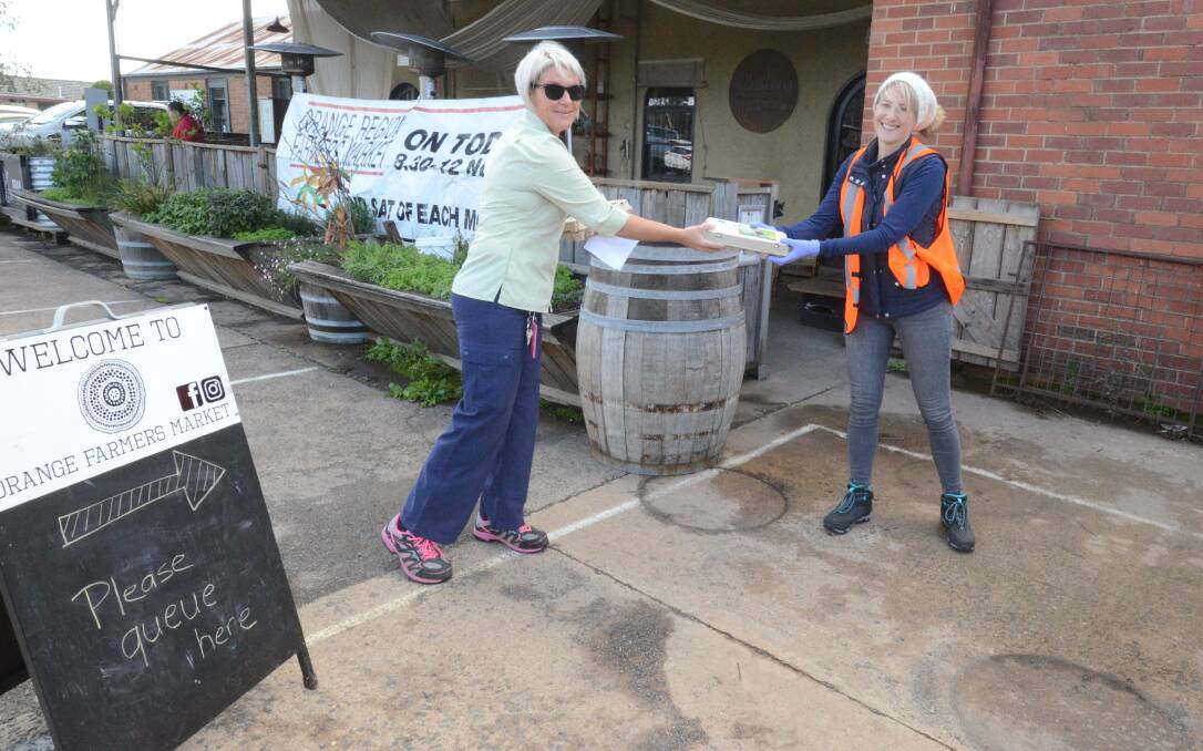 GRAB AND GO: Brooke Holmes stands back while she receives her purchase from Orange Farmers Market manager Holly Manning. Photo: JUDE KEOGH