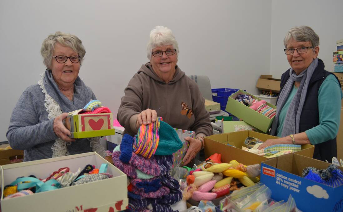 HELPING CHILDREN: Volunteers Joy Crowe, Elizabeth Kay and Jean Penrose filled boxes to give to children living in poverty during a Samaritans Purse Operation Christmas Child working bee on Saturday. Photo: TANYA MARSCHKE