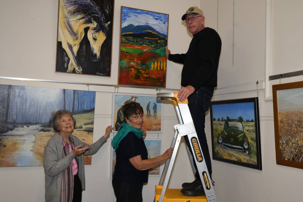 NEW LOOK: Orange Art Society members Jean Carney, Kay Partridge and Tony Kennedy hanging the paintings on Sunday. Photo: CARLA FREEDMAN