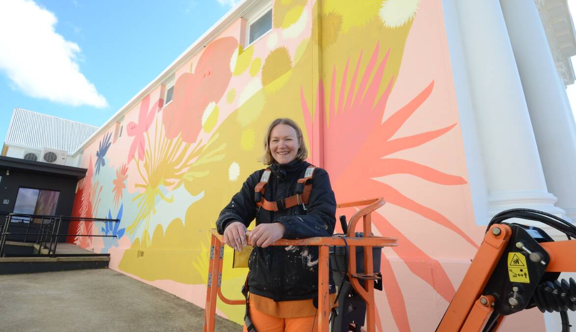 COLOURFUL: Mural artist Nastia Gladushchenko with her creation Sonic Bloom on the side of the Sonic building in Sale Street. Photo: JUDE KOUGH