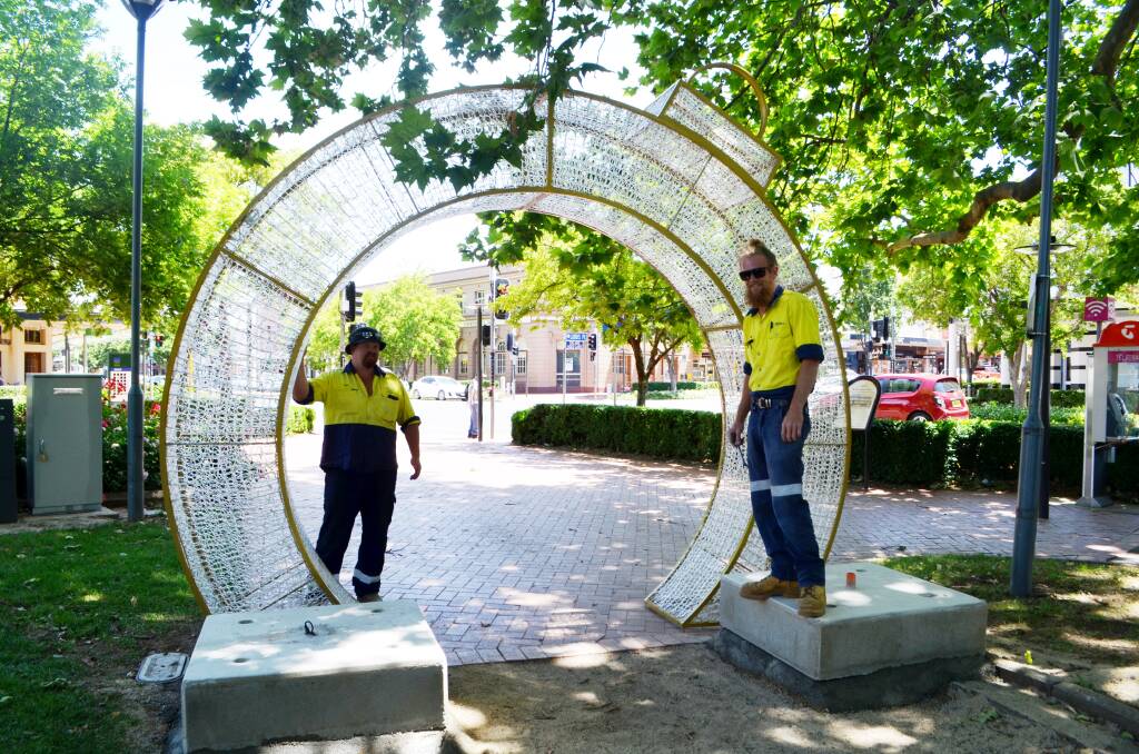 LIGHT THE WAY: Council electricians Matt Hunt and Quinn Luxford set up Christmas decorations in Robertson Park on Monday. Photo: SUPPLIED.