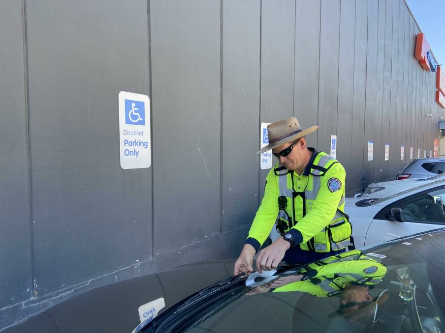 WARNING: Orange City Council parking officer Adrian leaves a note on a car that had parked in a disabled spot without displaying a ticket. Had he not seen the disabled permit inside the car, he would've issued a ticket. Photo: PETER HOLMES.