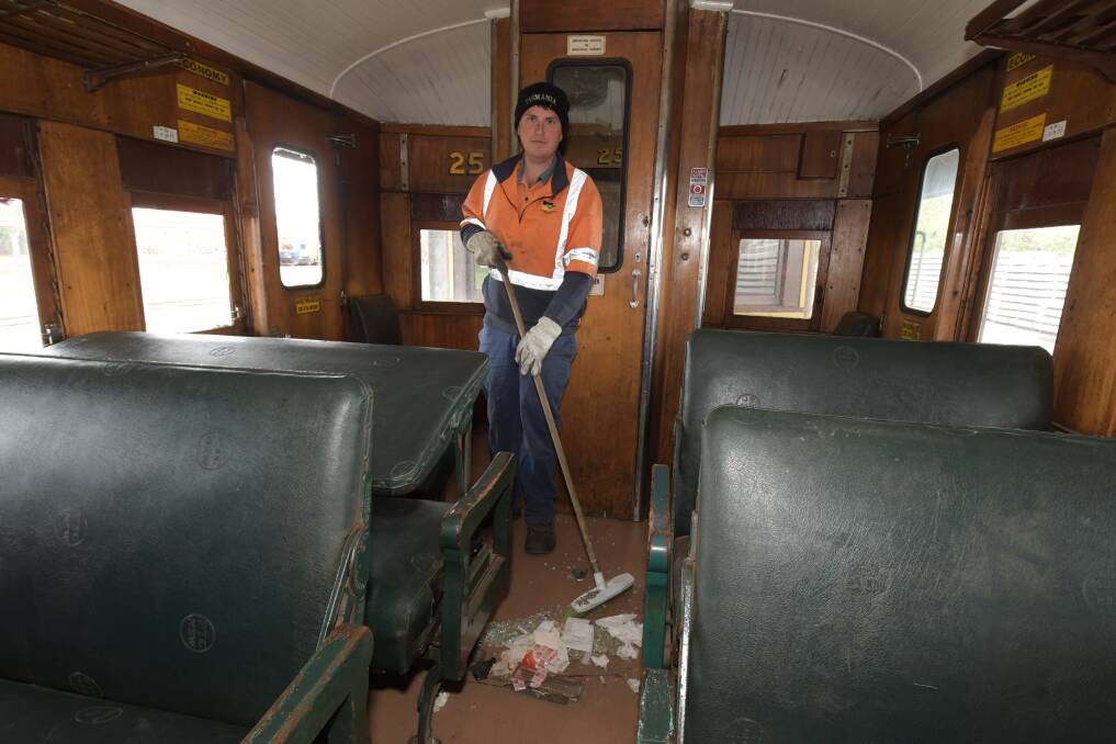 CLEAN SWEEP: Jack Holmes and the mess left by vandals who smashed windows on a train in October. Photo: CARLA FREEDMAN.