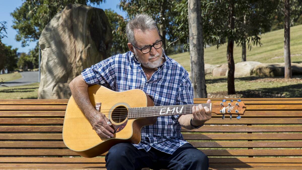 TRAVELLIN' MAN: John Williamson plays an E chord on his one-off "Emu" acoustic guitar, made by Maton. Photo: SUPPLIED.
