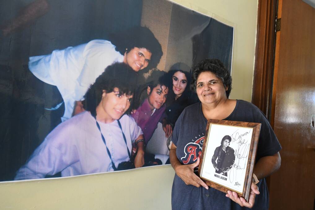 THRILLING: Carmen Nixon holding a Michael Jackson autograph, standing in front of a photo of her (back) with Mr Jackson in 1987. Photo: SUPPLIED. 