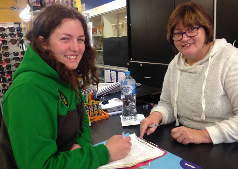 SUPPORT:  Alina Gfroerer signs the rail petition in TJs Newsagency with Dot Jones.