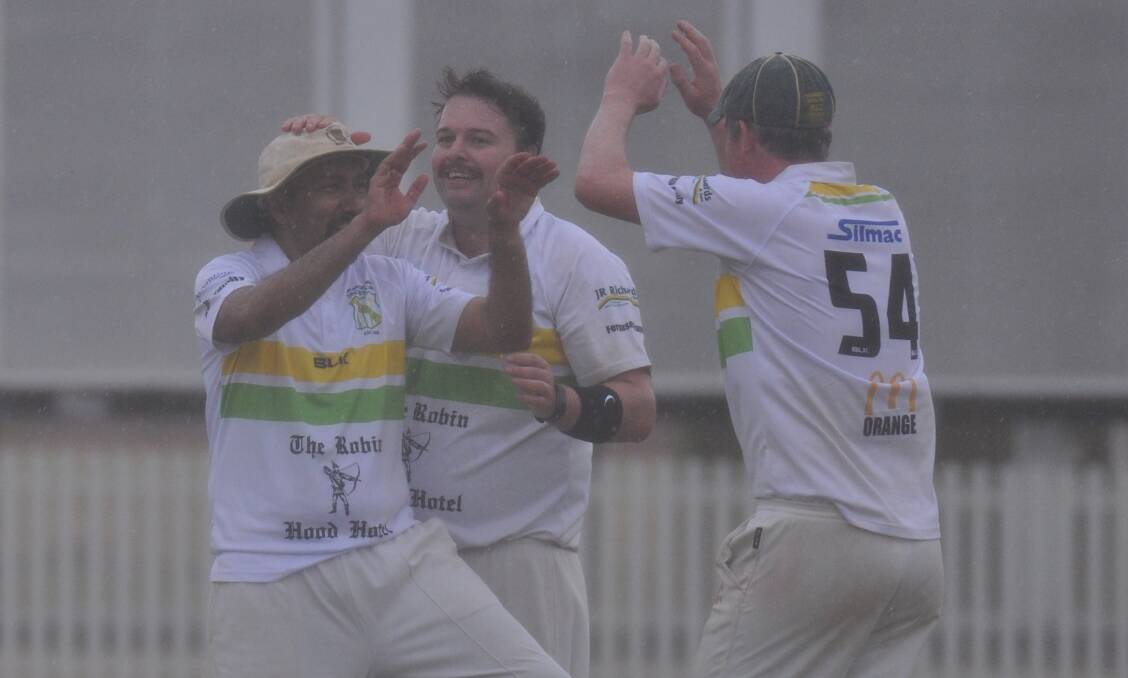DHATT OUT OF HELL: As the rain falls at Wade Park on Saturday Al Dhatt celebrates a wicket with Chris Novak and Dave Neil. Photo: NICK McGRATH