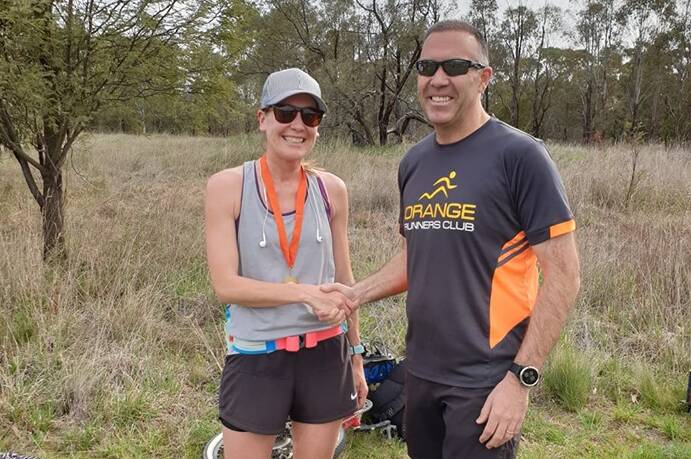 FLYING: Club president Anthony Daintith (right) presents Carissa Hickey with her 75-run medal, she won the 11.3km on Sunday and backed that up with the second fastest female time on Wednesday.