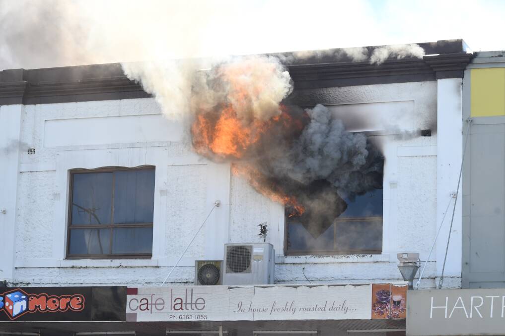 SPREADING: Flames and smoke erupt from the second-story window of a building on Orange's main street on Monday. Photo: CARLA FREEDMAN