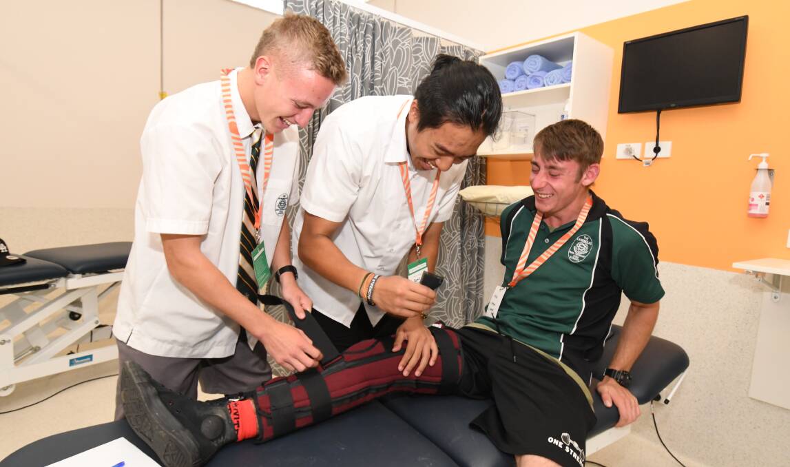 BRACE FOR IMPACT: Canobolas' Max Wilson, Ben Mangsa and Kyle Preddey get to work with a rigid knee brace. Photo: JUDE KEOGH