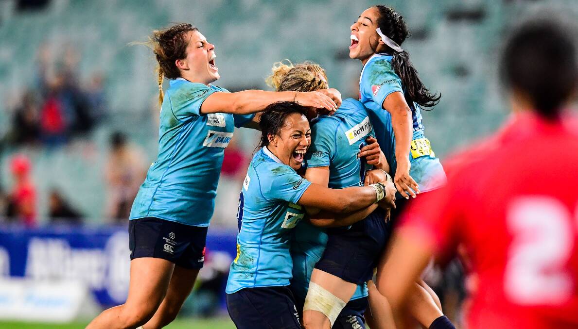 ABSOLUTE SCENES: Grace Hamilton (left) and her NSW Waratahs teammates mob skipper Ash Hewson after she landed a title-winning penalty goal in the 92nd minute of Friday's final. Photo: STUART WALMSLEY/ARU