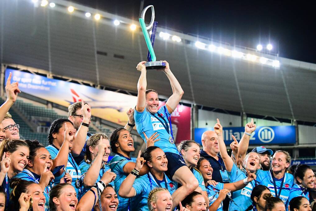 THE MATCH-WINNER: NSW Waratahs skipper Ash Hewson, chaired by her side, hoists the Super W trophy high after inspiring her side's epic win. Photo: STUART WALMSLEY/ARU