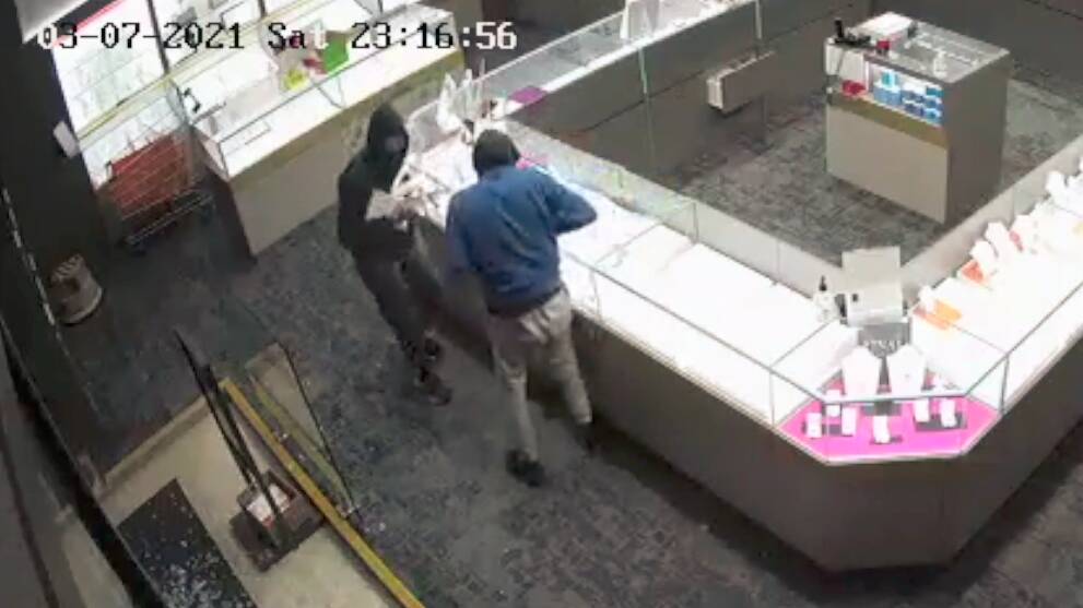 THEFT: CCTV footage from Angus and Coote in Orange shows two men smashing displaying cabinets and stealing jewellery. Photo: NSW POLICE