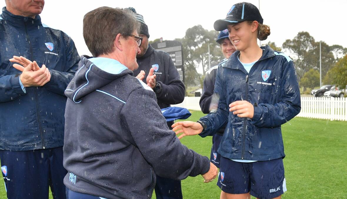BIG MOMENT: Phoebe Litchfield receives her baggy blue from Cricket NSW legend Kerry Marshall prior to Sunday's game, becoming the third-youngest NSW debutante. Photo: DAVID MARIUZ via CRICKET NSW