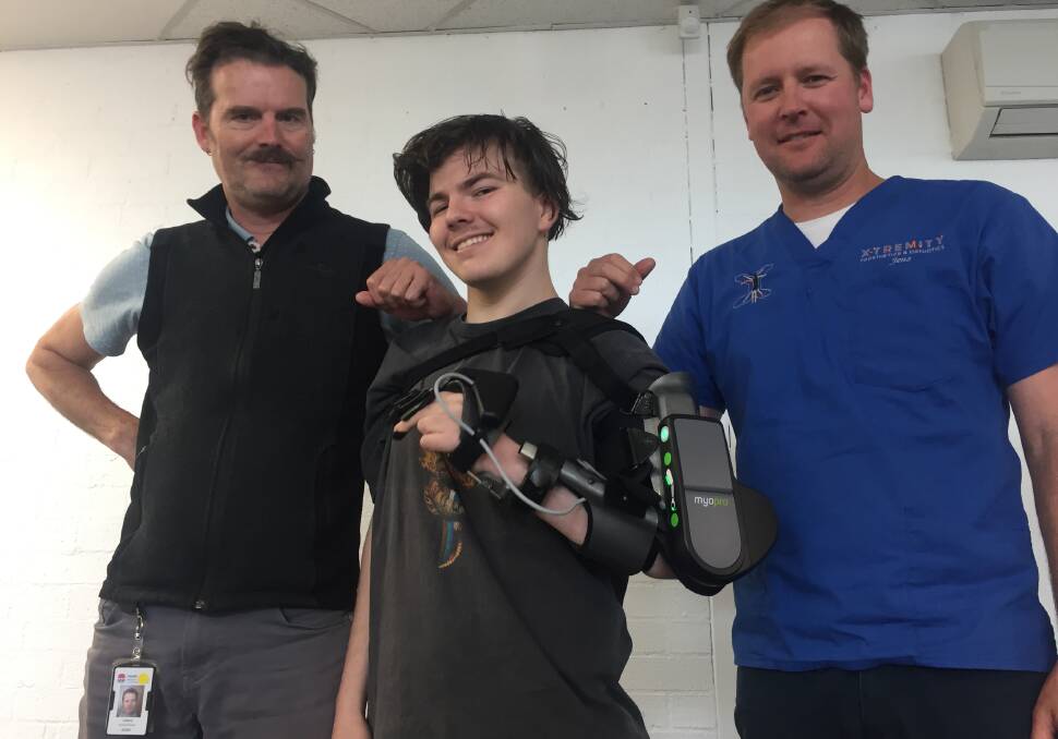 BIONIC MAN: Nineteen-year-old Khy Antoniazzo with his new MyoPro powered arm with his caseworker/physiotherapist Damien Barratt (left) and Jens Baufeldt, of Extremity Prosthetics and Orthotics in Nowra.