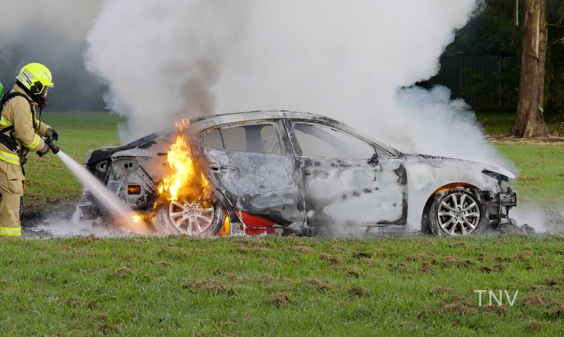 TORCHED: Fire crews extinguish the red Mazda that was stolen and set alight. Photo: TROY PEARSON