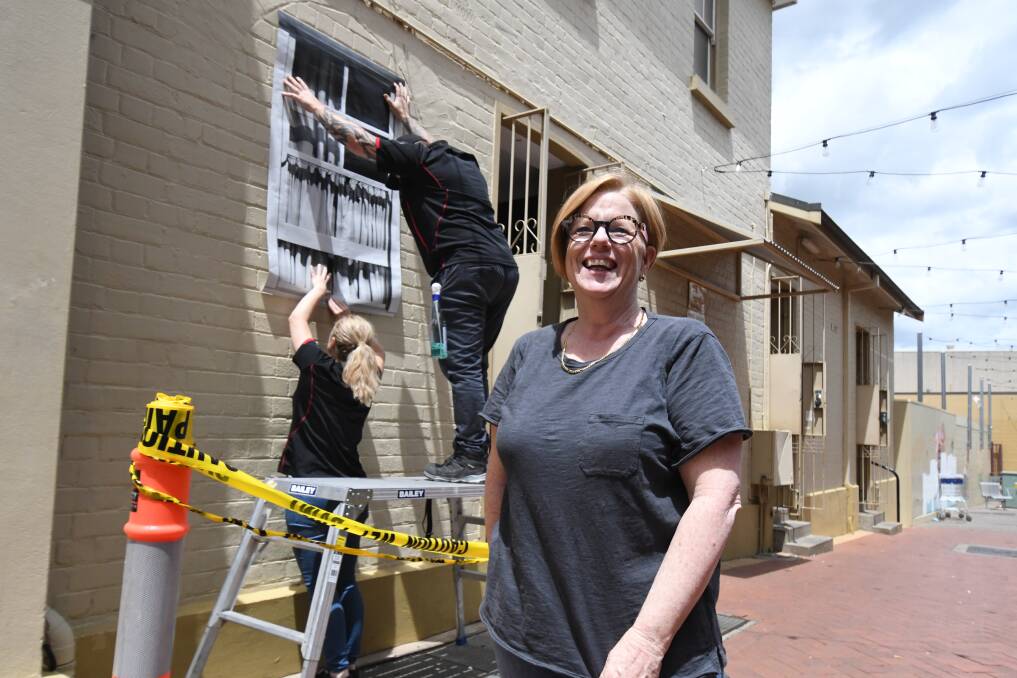CREATING ILLUSIONS: Artist Catherine O'Donnell and her team Bianca Stevens and Graeme Doolan from Tint and Protect install a 'window' in Post Office Lane. Photo: JUDE KEOGH