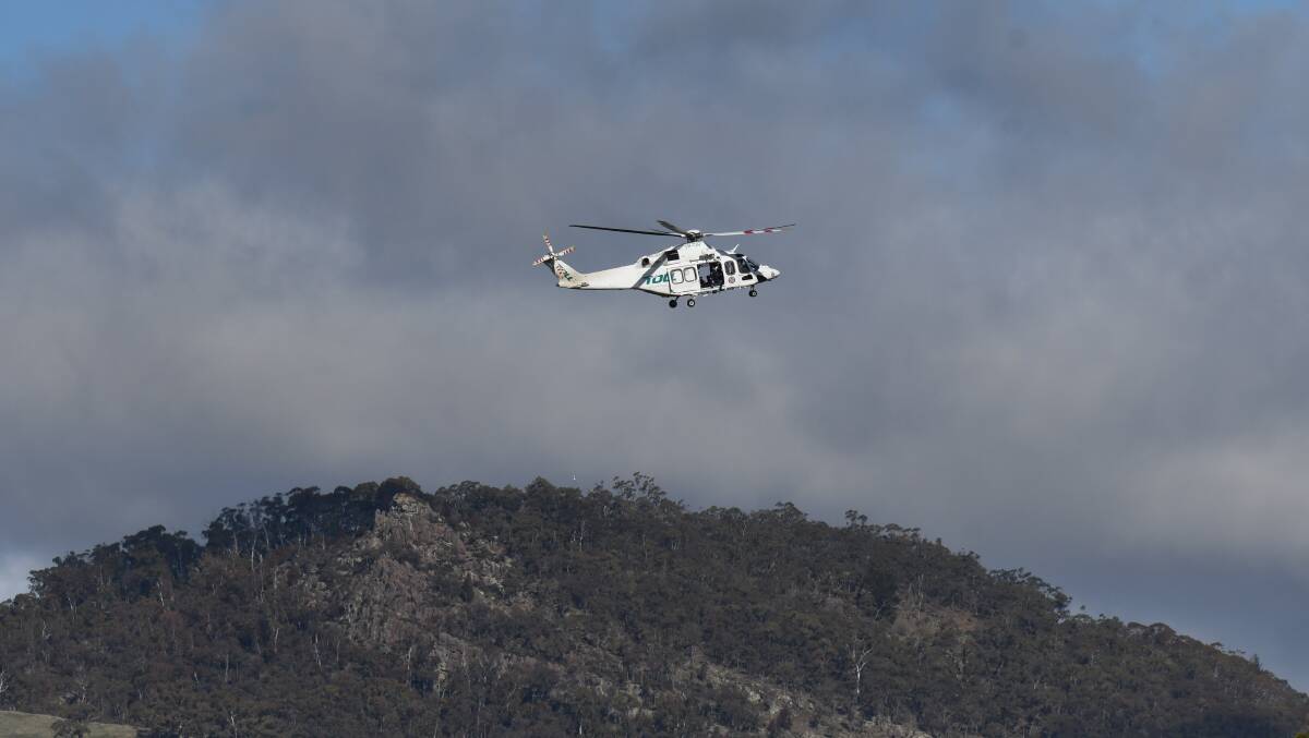 AIRLIFTED: The helicopter near Mount Canobolas on Thursday. Photo: JUDE KEOGH