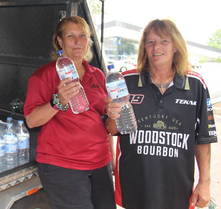 GIVING WATER: Tania Hodgkinson and Maree Glohe at the northern end of Robertson Park on Saturday collecting water to travel to Walgett. Photo: MAX STAINKAMPH