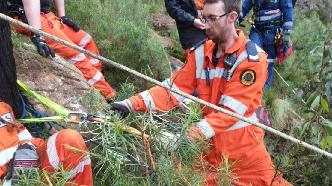 HELPING HAND: SES volunteer Zack Schneider assists in extracting a teenager from Mount Canobolas. Photo: SES