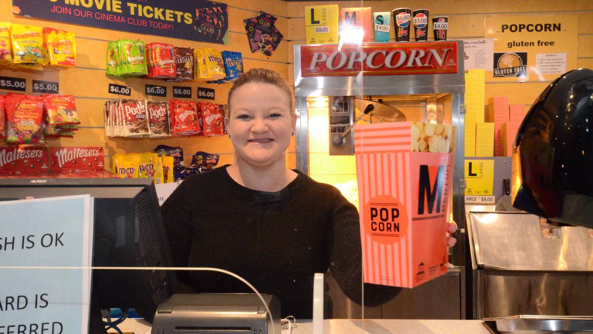 BACK IN BUSINESS: Mitzi Cronk behind the candy bar at Odeon 5 Cinema, with screens in place for protection of staff. Photo: JUDE KEOGH