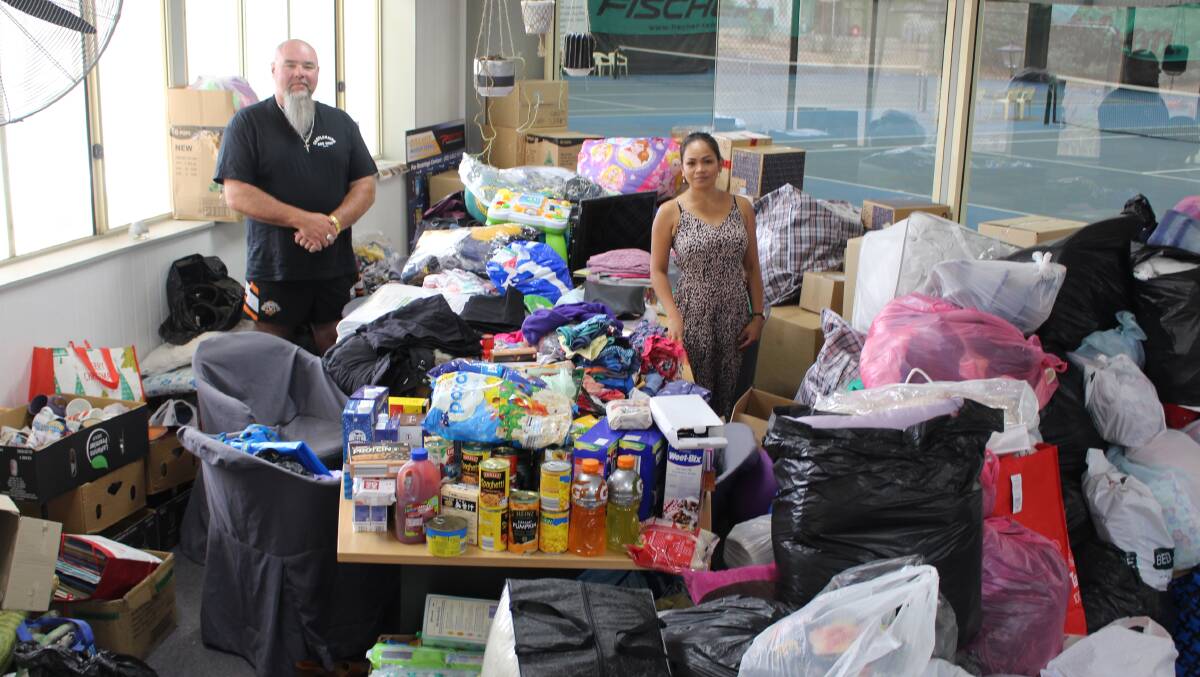 THANKFUL: Jason Smith and Lioba Besgrove with the mountains of donations for bushfire victims at the Orange Tennis Centre. Photo: MAX STAINKAMPH