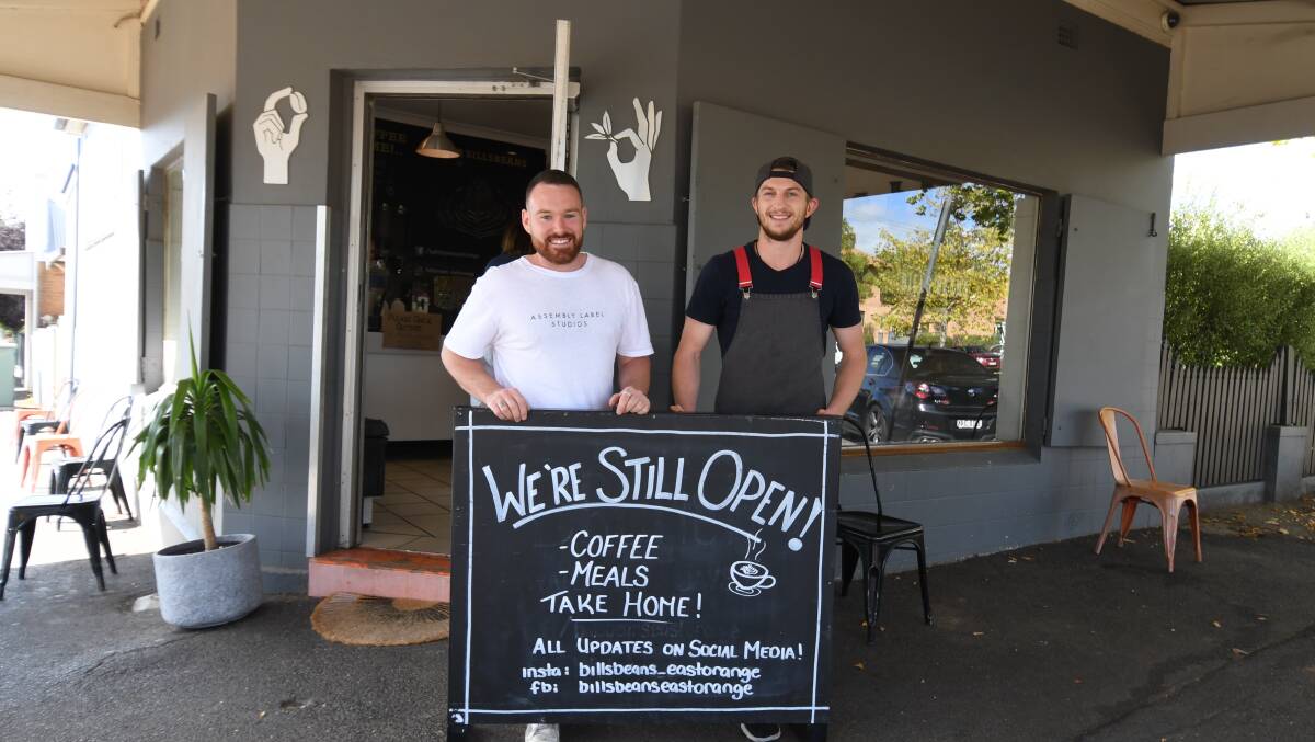 OPEN FOR BUSINESS: A relieved Ricky Carver and Carter Hirini out the front of Bills Beans on Monday, which will stay open as a takeway-only venue. Photo: CARLA FREEDMAN