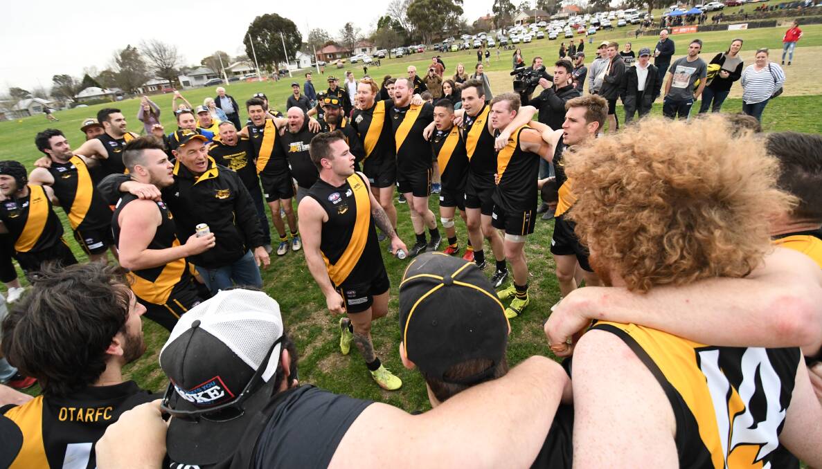 OH WE'RE FROM TIGERLAND: Chris Rothnie arm in arm with Tigers legend Mark Byrne with brother Michael in the centre of the huddle on George Park. Photo: CHRIS SEABROOK. 
