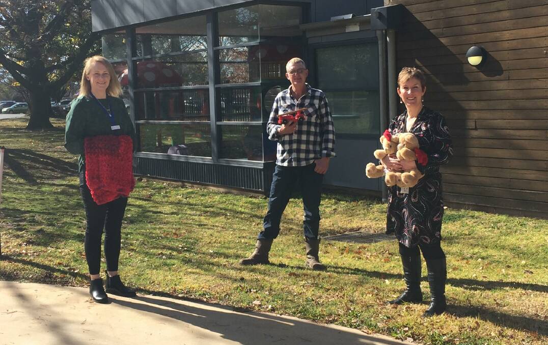 GETTING RED-DY: Bronwyn Cooper, David McDonell and Rebecca Walsh out the front of the Ronald McDonald House ahead of Wear Red Day on Thursday. 