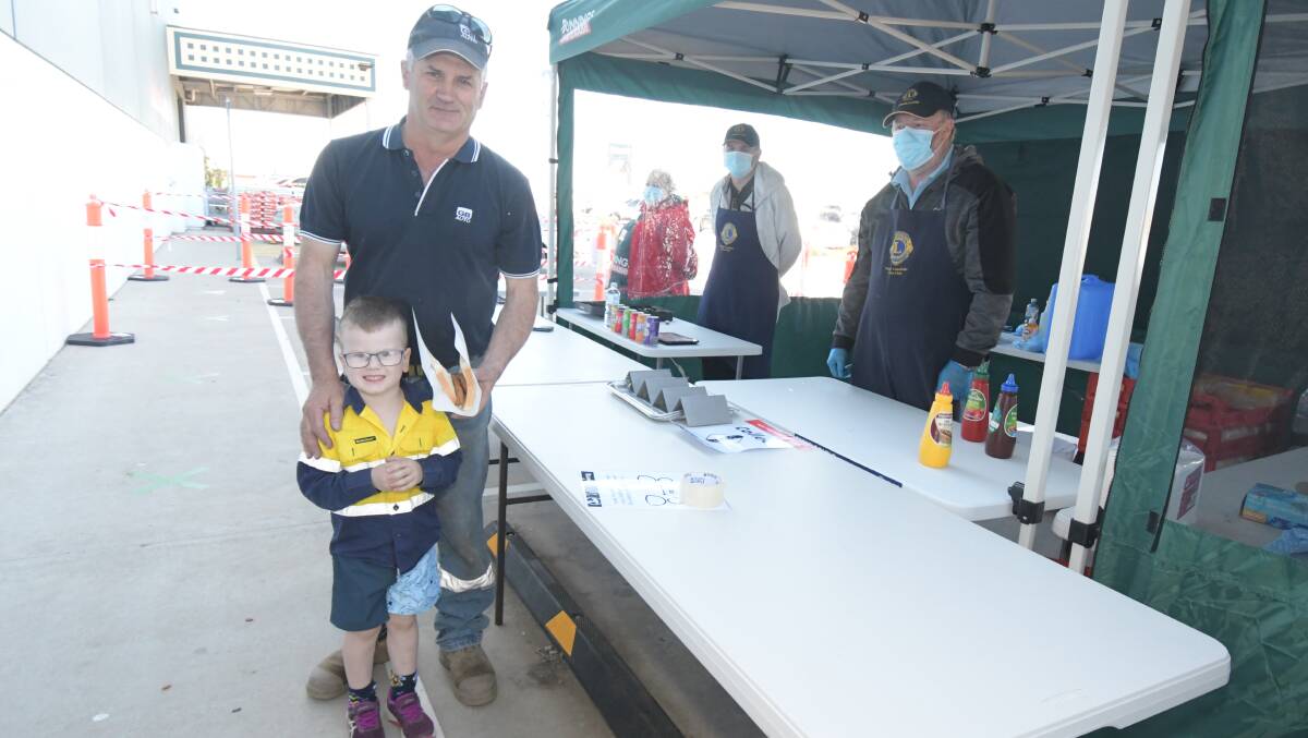 BACK AT IT: Graeme Bensley and his grandson Felix West tuck into a snag each on Saturday morning, with Brett Campbell and Brendan Curran watching on. Photo: JUDE KEOGH