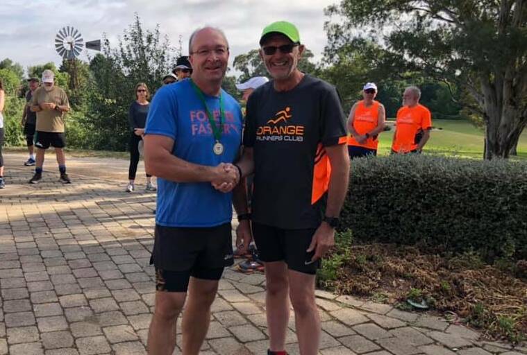 AMAZING ACHIEVEMENT: John Connolly been presented his 800 run achievement medal from Vice President Greg Shapter at the Botanic Gardens. Photo: SUPPLIED