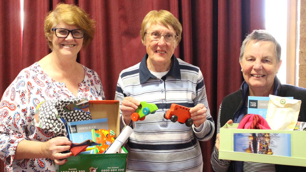 HELPING HANDS: Pam Johnson, Marj Strong and Jenny Root with gift boxes and toys for Operation Christmas Child. Photo: MAX STAINKAMPH
