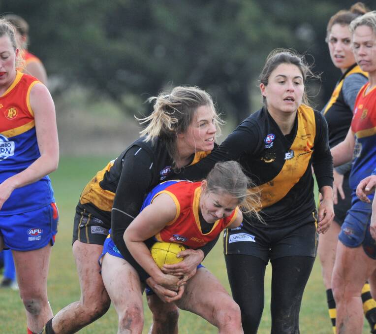 BIG TIME: Jemma Neuman and Aspasia Manos with the tackle on the Dubbo Demons player during a victory for the Orange Tigers. Photo: JUDE KEOGH. 