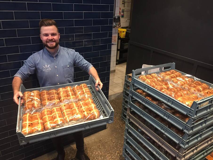 YUM: Taylor Stevenson is the operations manager at Village Bakehouse who have been selling hundreds of hot cross buns. Photo: RILEY KRAUSE.