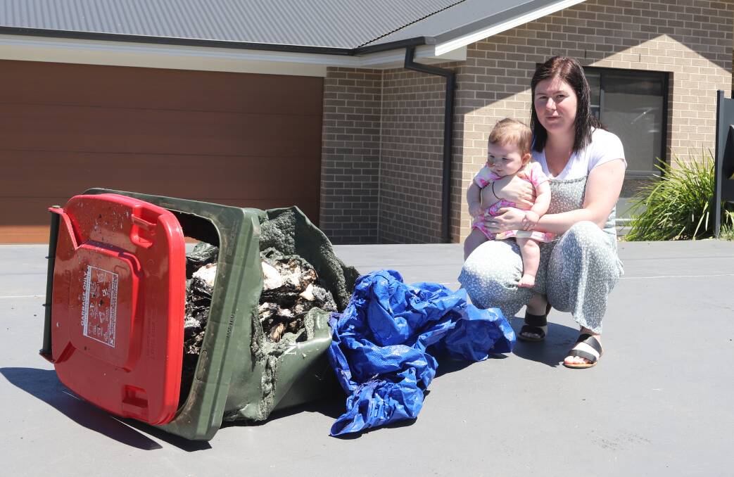 FURIOUS: Paige Palmer and daughter Eedie-Rose Rossiter with the bin that was set on fire at their house last Friday night. Photo: CARLA FREEDMAN.