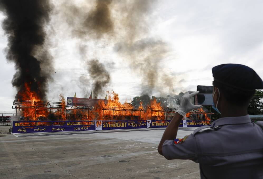 A police officer takes a photo of the burning of US$839 million worth of seized drugs in Myanmar last year. Picture: EPA