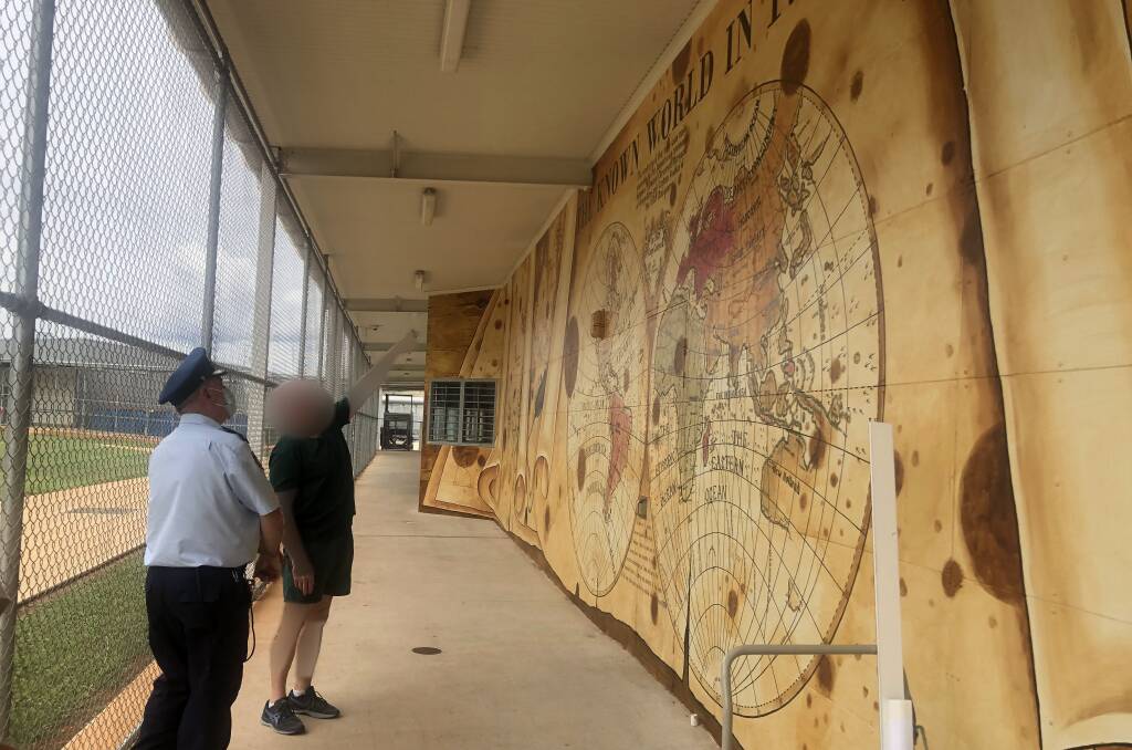 Inmate and art teacher John points out details of one of his murals to an officer. Picture supplied