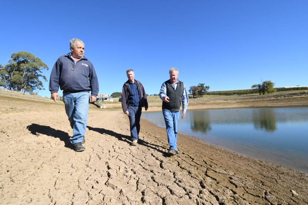 BONE DRY: Guy Gaeta, Peter West and Bruce Reynolds at orchardist Bernard Hall's dam, which is showing the effects of the recent lack of rain. Photo: JUDE KEOGH