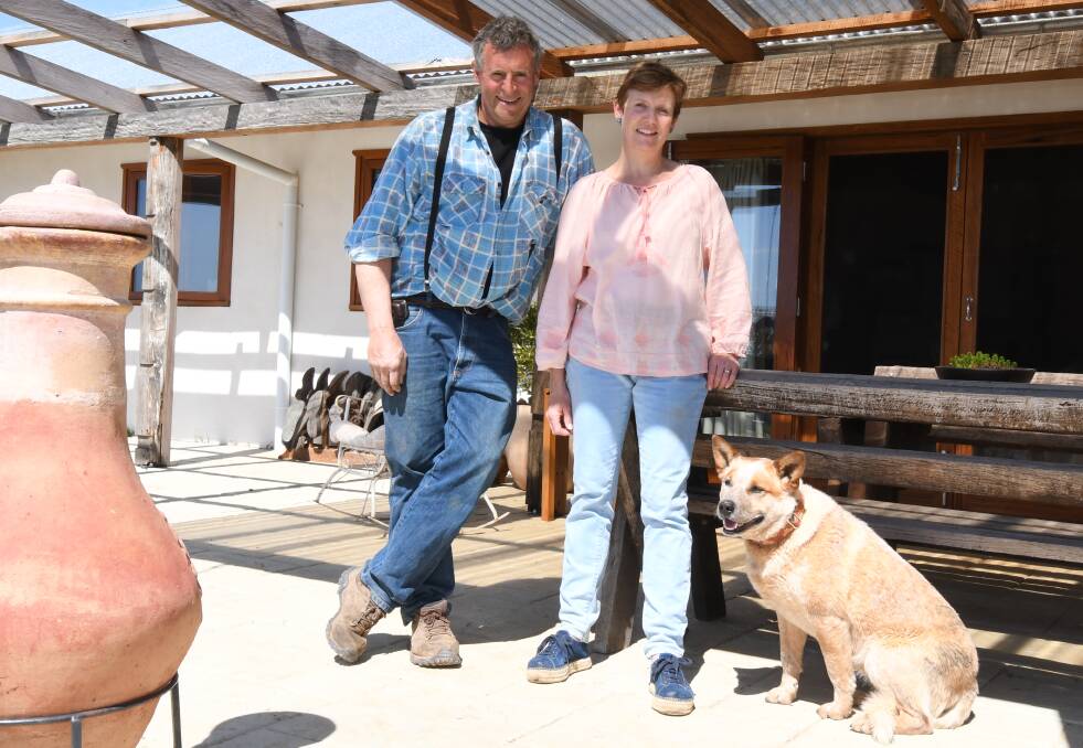 OFF GRID: Looking out over Orange, Wayne and Karyn Vardanega catch some sun rays with Sadie the red cattle dog during a sustainable open home day on the weekend. Photo: CARLA FREEDMAN