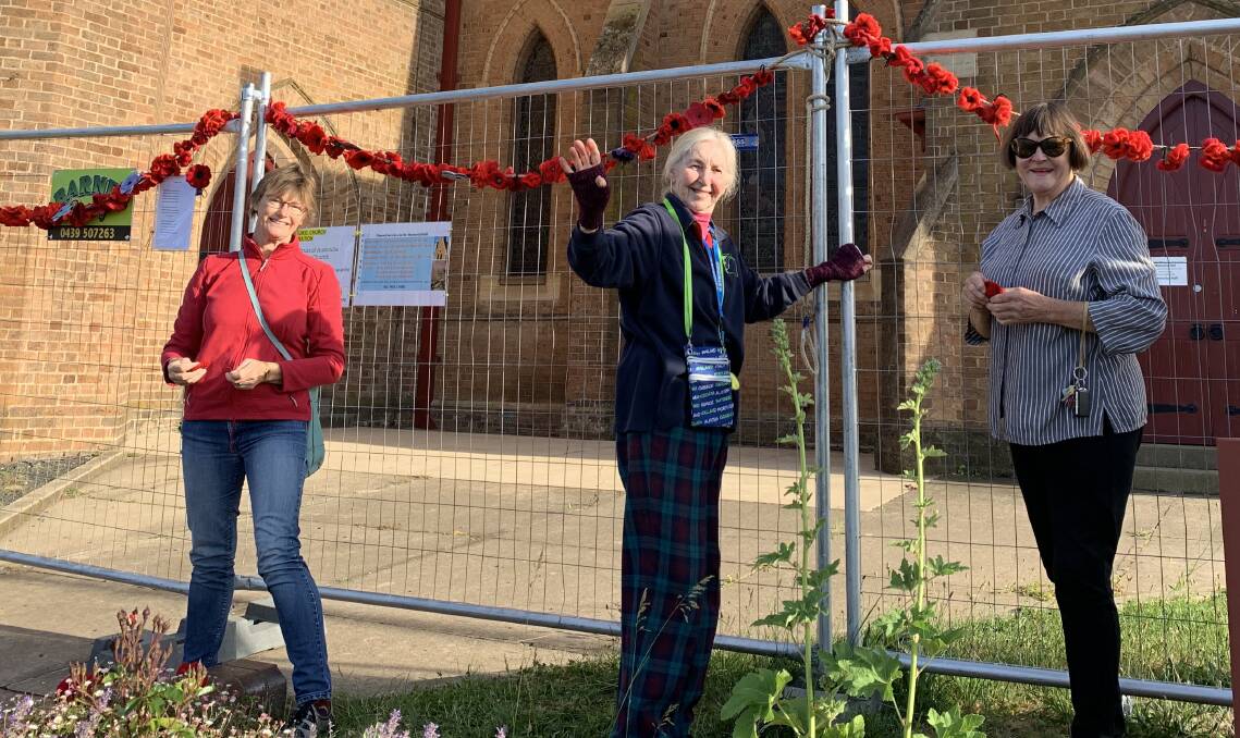 REMEMBRANCE DAY: Michelle Englart, Joy Fabry and Libby West hung poppies from the fence at Holy Trinity Anglican Church on Monday. Photo: SUPPLIED