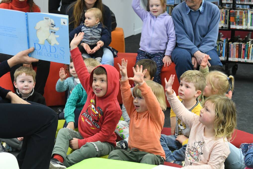 HANDS UP: Little bookworms respond to Fiona Hawke's enquiries during one of the Storytime events held regularly at the library. Photo: JUDE KEOGH 2808jklibrary2