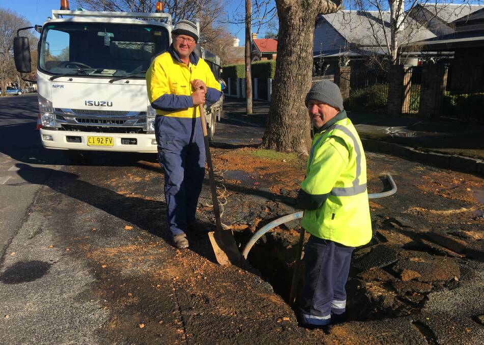 BURST PIPE: Orange City Council workers Brett Beasley and Peter Stibbard at work to repair damage done to a water pipe. Photo: ALEX CROWE