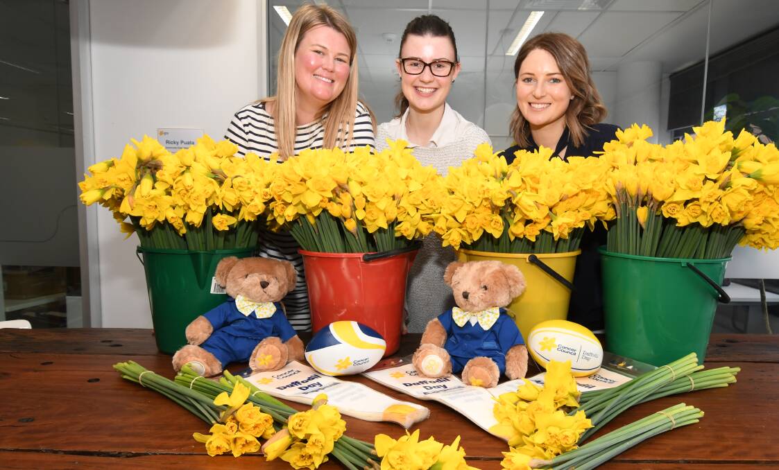 DIG DEEP: Cancer Council's Bree Kelly, Emma Robinson and Nicola Taylor spring into the 33rd Daffodil Day fundraiser. Photo: JUDE KEOGH