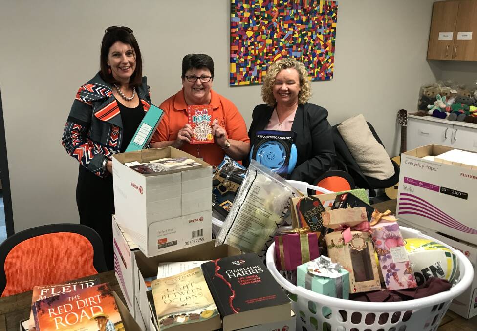CHRISSY HAMPERS: Sharon Lord, volunteer Narelle Gordon and Christine Whybrow pack books and toys from Yates Baker McLean. Photo: SUPPLIED