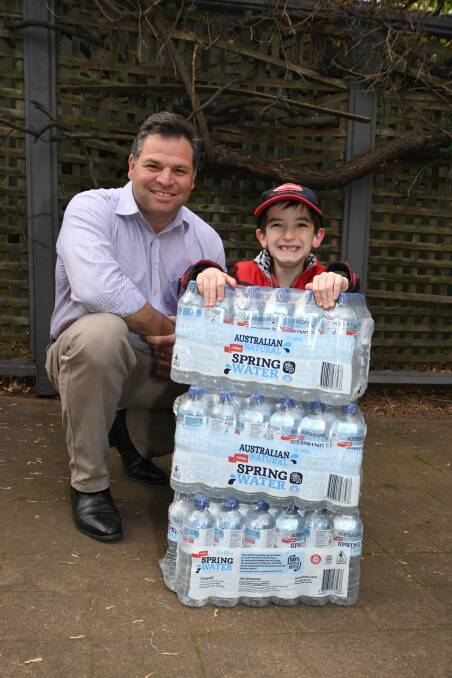 DONATION DROP: Member for Orange Philip Donato accepts a donation of three cases of 24 water bottles from Murphy Sims. Photo: Carla Freedman 0724cfmurphysims8