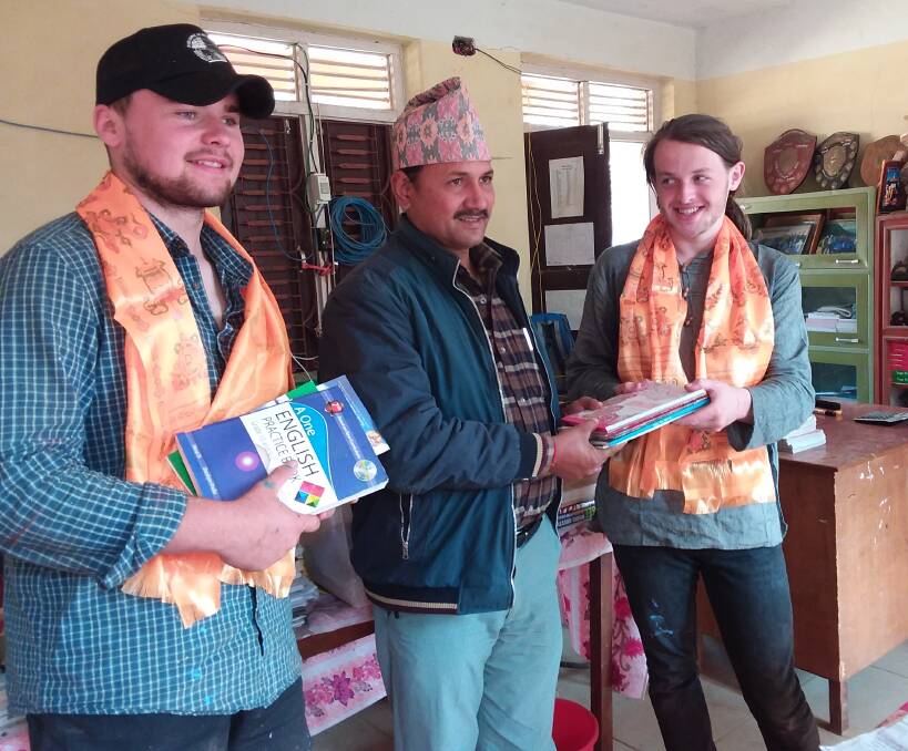 HAND OVER: Sam Mackie and Lachlan Fenemor hand over a collection of books to a Nepalese teacher. Photo: supplied.
