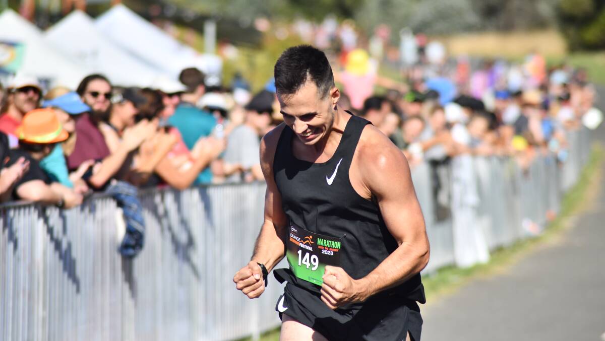 Zac Rosser does a double fist pump after finishing first in the Orange Running Festival marathon. Picture by Jude Keogh 