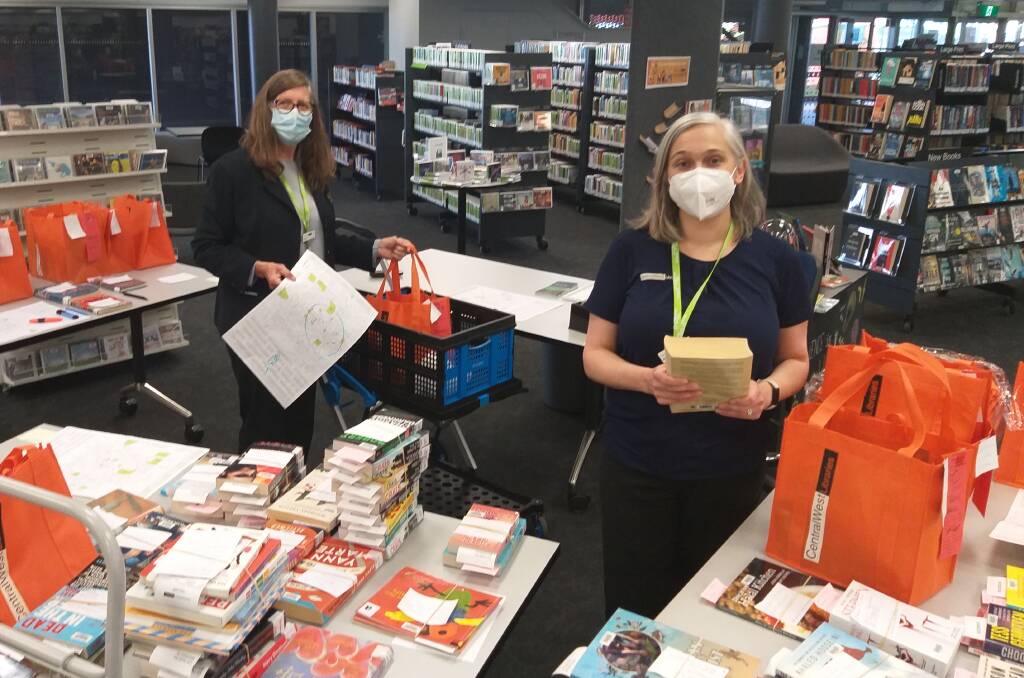 BOOKS TO YOUR DOOR: Cecilia Lawler Alex Gibb prepare home delivery orders for library customers. PHOTO: SUPPLIED