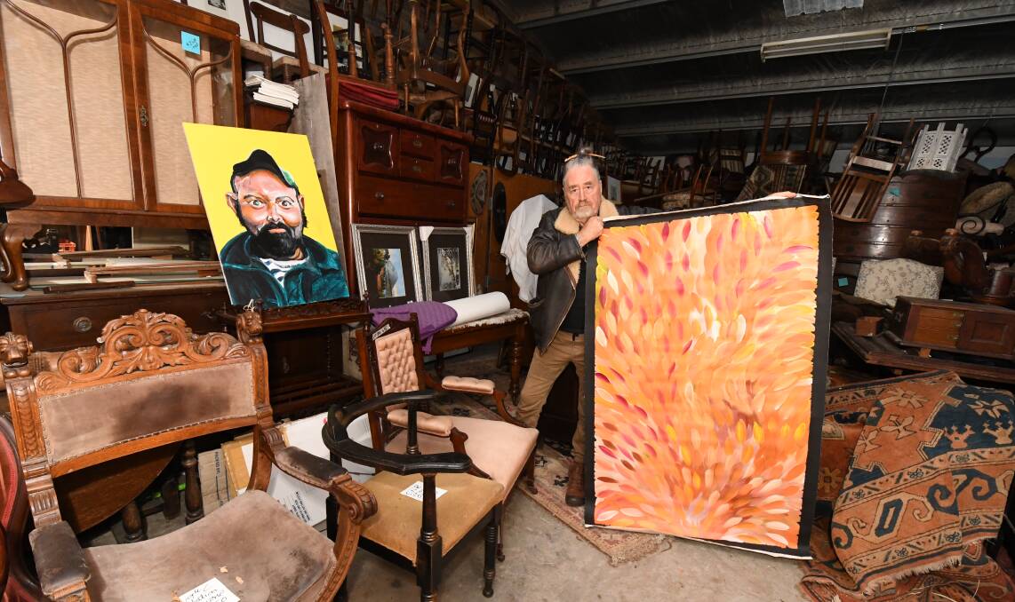 Steve Archer holds up some of the original art by Gloria Pettyarre and Adam Cullen which he is selling. PHOTO: JUDE KEOGH 